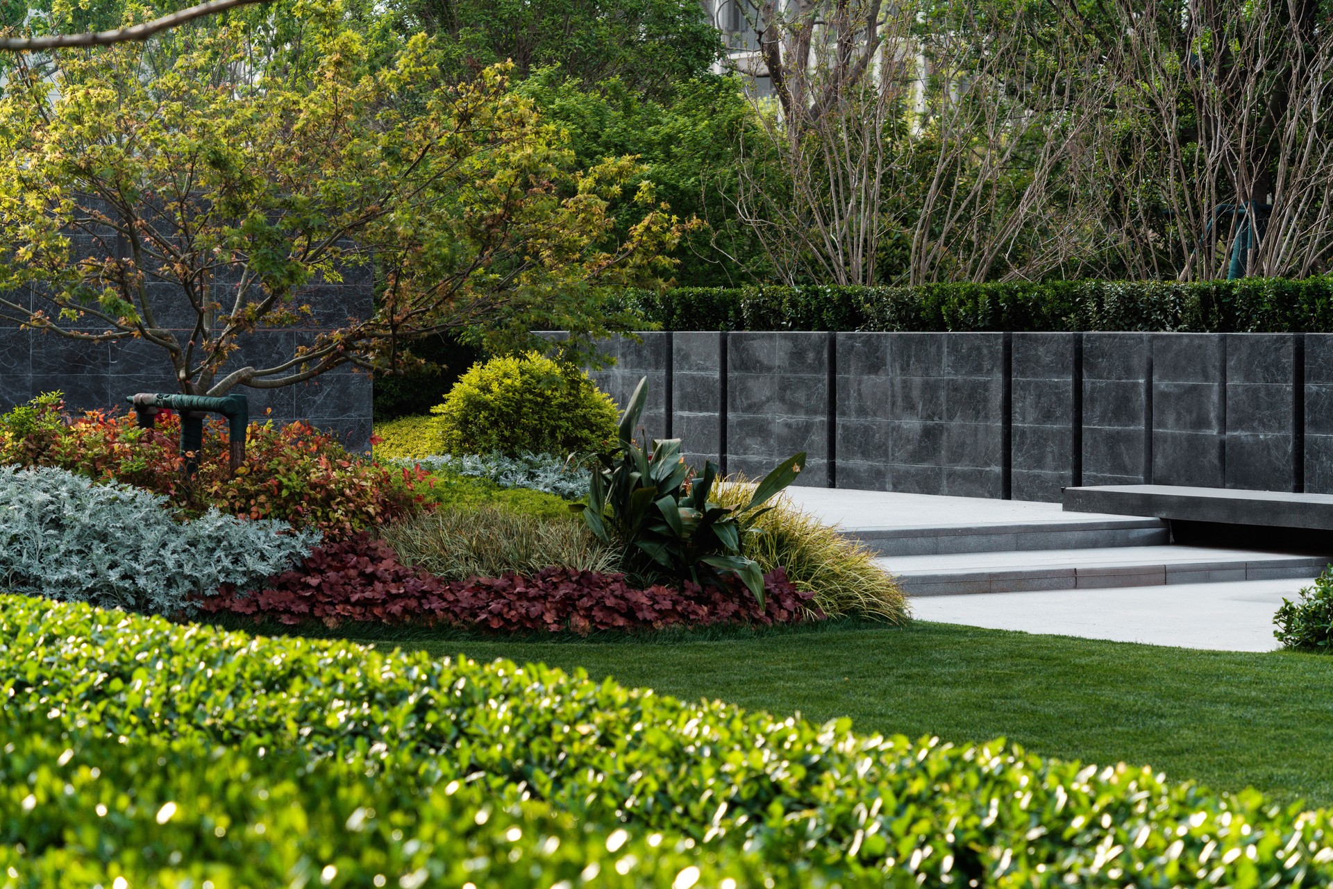 Well-maintained community garden with dense flower beds, neatly trimmed hedges, and rich seasonal color.